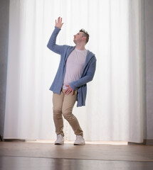 Young guy dancer in motion in a pose. A man performs a modern dance in casual clothes.