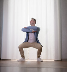 Young guy dancer in motion in a pose. A man performs a modern dance in casual clothes.