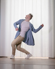 Young guy dancer in motion in a pose. A man performs a modern dance in casual clothes.