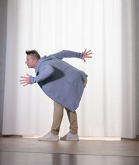 Young guy dancer in motion in a pose. A man performs a modern dance in casual clothes.