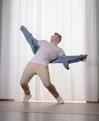 Young guy dancer in motion in a pose. A man performs a modern dance in casual clothes.