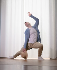 Young guy dancer in motion in a pose. A man performs a modern dance in casual clothes.
