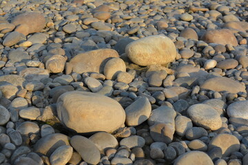 Sunset over the Dead Sea coast with stones, pebbles, and waves along the shore in a serene mountain landscape