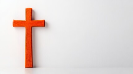 Naklejka premium Orange wooden cross on a white background, simple religious imagery.
