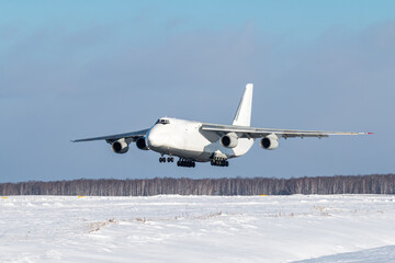White wide body transport cargo aircraft approaches for landing at winter airport