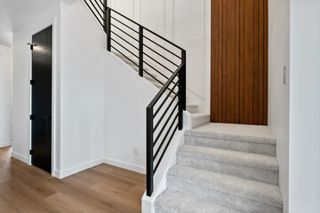 A staircase with a black railing and a wooden door