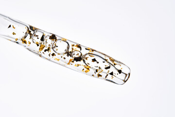 24 k gold facial serum in a pipette on a white background.