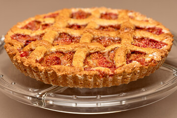 A golden homemade fig tart with a crispy lattice crust, baked to perfection and served on a clear glass plate, showcasing its rustic charm