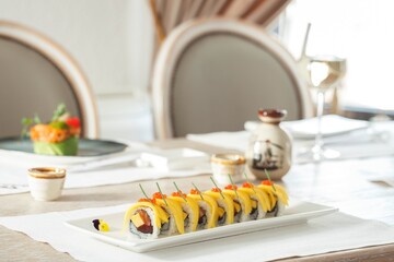 Under soft lighting, guests savor beautifully plated sushi rolls, adorned with fresh ingredients...