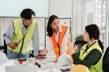 Construction team in safety vests engaged in detailed discussion of building plans in modern office