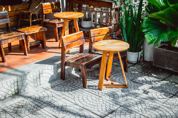 Rustic wooden outdoor furniture set in sunlit patio with green foliage