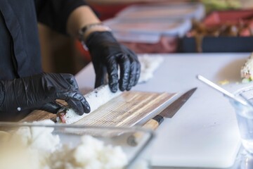 Expert hands skillfully roll sushi using top-quality ingredients in a lively sushi restaurant. Attention to detail and passion for cooking shine through as culinary art is created for diners