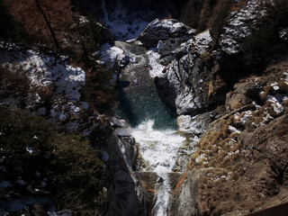 Stunning aerial view of lillaz waterfall cascading into a vibrant turquoise pool, surrounded by snow dusted rocks and trees in the aosta valley, italy Lillaz