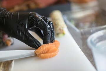 Fresh salmon slices are skillfully prepared by a talented chef at a well-known sushi restaurant,...