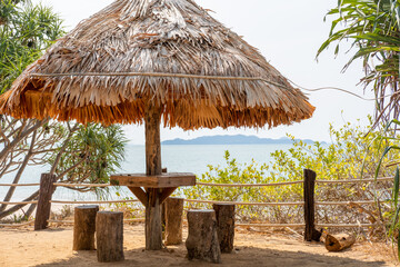 Seating under a wooden hut shelter, located by the sea.