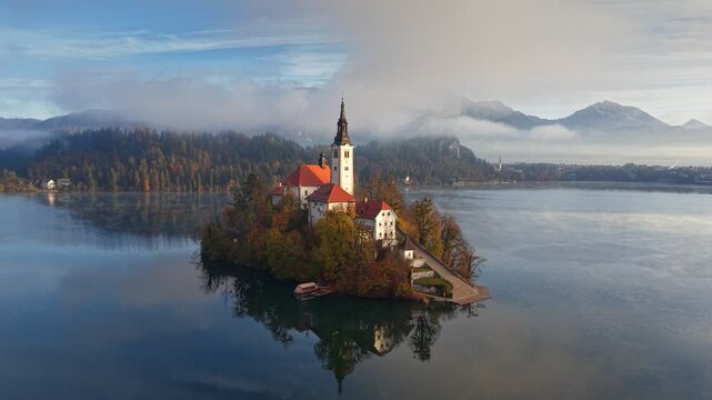 Bled lake in Slovenia, aerial shot, autumn. Island Bled with Pilgrimage Church and Bled Castle in morning light. Bled Island in Slovenia, showcasing iconic church and vibrant autumn trees