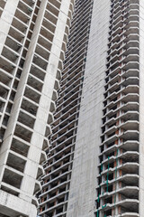 Tall concrete building under construction with unfinished structure and scaffolding