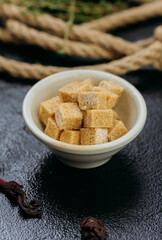 Brown sugar cubes in ceramic bowl elegantly presented on dark background for rustic cozy aesthetic