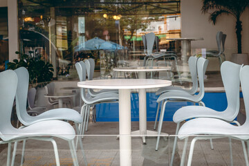 Modern outdoor cafe with white chairs and glass wall