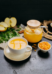 Sea buckthorn tea with apple and mint in glass teapot on rustic background, perfect for wellness