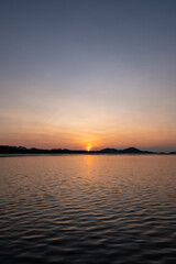 Sunrise view with colorful sky and the sea, with silhouette of the forest on the background