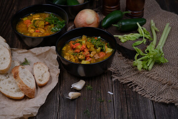 Celery, potato and carrot soup in black bowls in a rustic setting on wooden table
