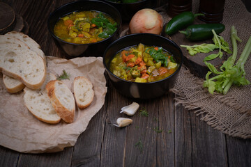 Celery, potato and carrot soup in black bowls in a rustic setting on wooden table
