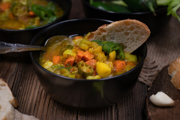 Celery, potato and carrot soup in black bowls in a rustic setting on wooden table