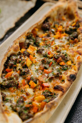 Turkish pide with minced meat, vegetables and cheese on a plate in a stylish restaurant setting