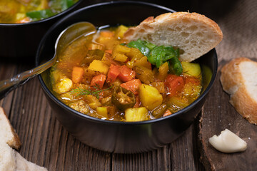 Celery, potato and carrot soup in black bowls in a rustic setting on wooden table