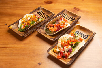 Assorted gourmet tacos arranged on wooden plates with artistic presentation