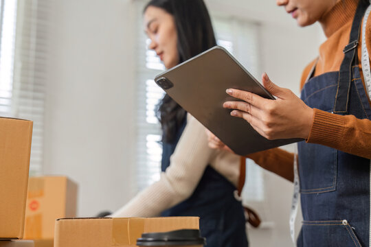 Two diverse warehouse workers organizing packages and managing inventory with a tablet.