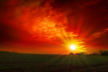 Red sunset background with sun and big abstract clouds.