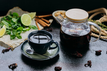 Aromatic herbal tea with cinnamon, mint, lime, and hibiscus in a stylish teapot and cup setting
