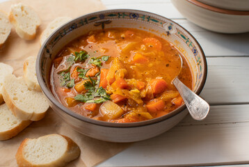 Vegan lentil and vegetables  soup bowl on wooden table