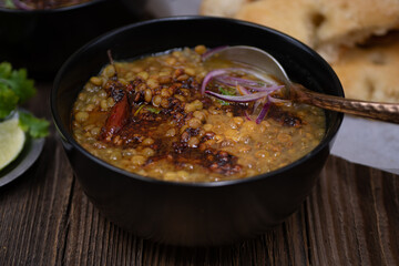 Vegan split green pea soup with tempered spices, flat breads on wooden table, copy space