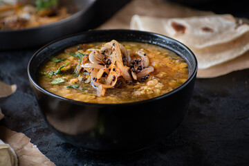 Vegan split yellow pea soup with caremelized onions, flat breads.  Black background, copy space