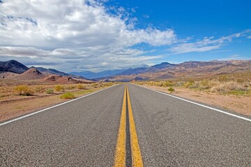 A long desert road disappearing into the distant mountains of Arizona