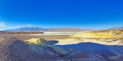 Vast desert landscape under a bright blue sky with distant mountains
