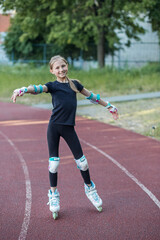 Obraz premium Preteen girl roller skating on track with protective gear in sunny park setting