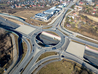 Krakow, Poland. Wegrzce interchange on new S52 highway (below) opened in December 2024. Part of freeway around Cracow. Traffic circle with a hole inside and ramps. Aerial view in February 2025