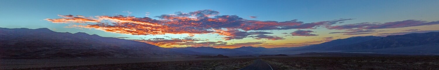 Fototapeta premium Scenic desert road at sunset with colorful clouds and mountain backdrop