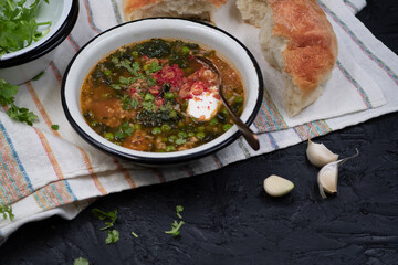 Spinach green peas and brown rice soup topped with sour cream, served in enameled bowl with home baked bread