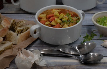 Potato, carrot and lima beans soup in white bowls on wooden backround, served with herb bread