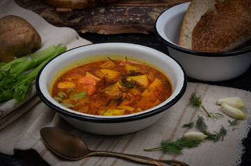 Celery, carrot and potato soup in ebameled bowls on dark table, copy space