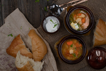 Vegatarian potato, carrot and celery soup served with cream on a rustic wooden table, along with bread