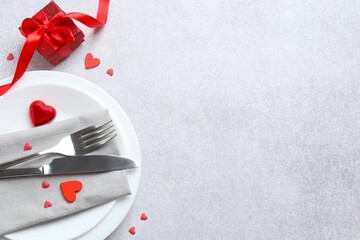 Festive table setting with gift box on gray background. Valentines day dinner concept. View from above. Copy space