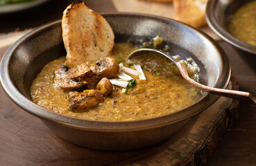 Vegan cream of mushroom soup on wooden table along with toasted bread and avocado