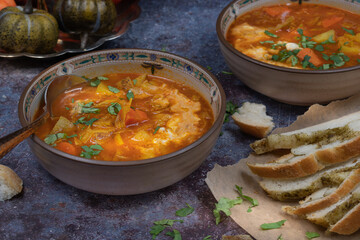 Vegan or vegetarian soup in ceramic bowls with herbed bread on gray table