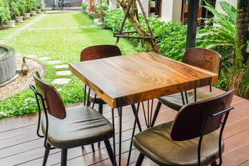 Wooden table and chair set in garden on a sunny day,outdoor seating for restaurant or cafe,Neat paved patio with sitting area and small garden in forest..